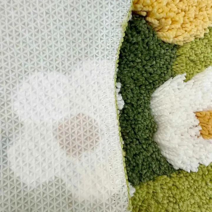 Detalhe da textura tufted e da base emborrachada do tapete de margaridas