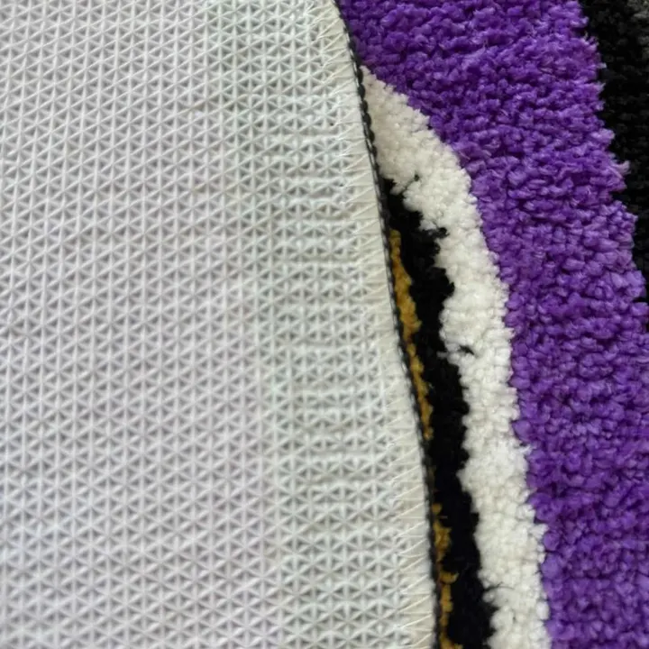 Detalhe da textura tufted e da base emborrachada do tapete isqueiro roxo